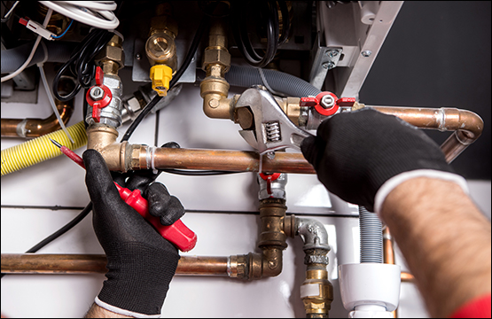 Picture of plumbers hands tightening nut on plumbing work with adjustable wrench.